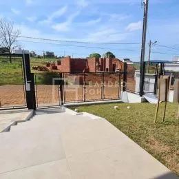 Vista externa do terreno com piso de concreto e gramado ao lado de uma cerca de tijolos.
