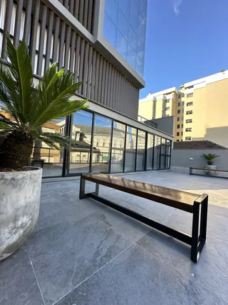 Vista externa de uma área de lazer com piso de concreto e um banco de madeira.