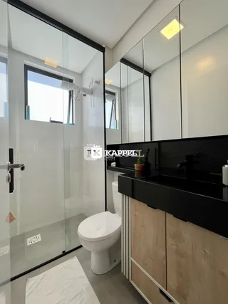Banheiro moderno com box de vidro e bancada escura.