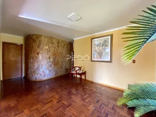 Sala de estar com piso de madeira e parede de pedra decorativa.