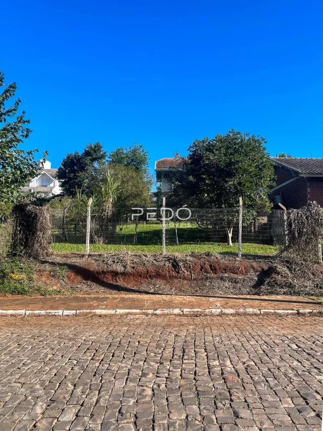 Vista externa de uma propriedade com cerca e vegetação no fundo.