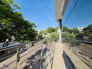 Vista de uma varanda com grade de metal e vegetação.