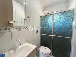O interior de um banheiro com revestimento cerâmico e divisória de vidro.