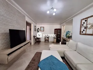 Sala de estar com sofá branco e televisão em ambiente claro.