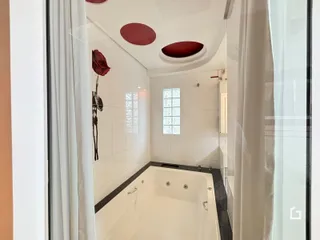 Foto interna de um banheiro com banheira branca e revestimento de azulejos brancos.