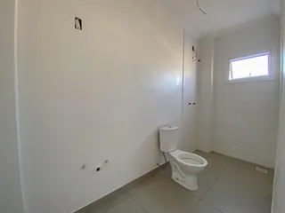 Foto de um banheiro interno com piso de cerâmica e vaso sanitário branco.