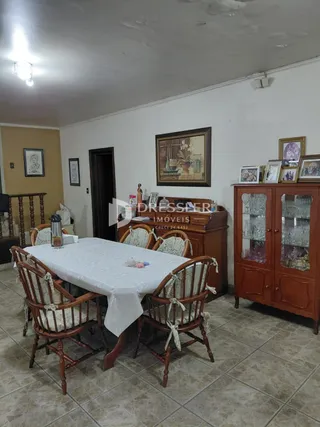 Uma mesa de jantar com cadeiras de madeira está no ambiente.
