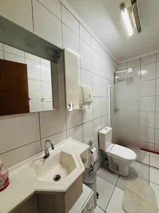 Foto de um banheiro com revestimento cerâmico branco e louças sanitárias.