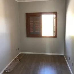 Sala de estar com piso de madeira e janela grande.