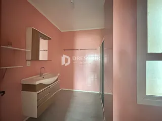 Foto interna de um banheiro com paredes rosa e piso cinza claro.
