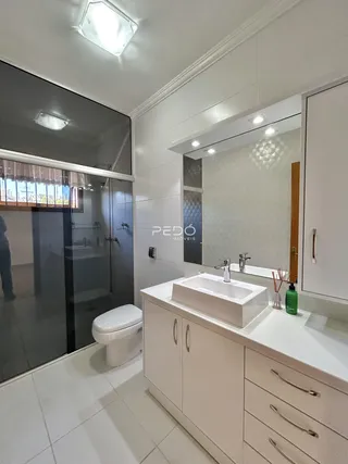 Interior de um banheiro moderno com box de vidro e revestimento branco.