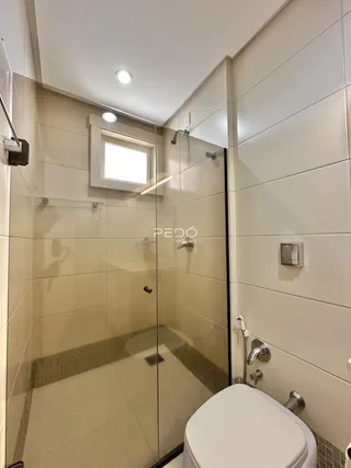 Foto de um banheiro com box de vidro e revestimento cerâmico.