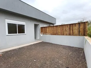 Fachada externa de uma residência em Lajeado, Brasil, com muro de madeira e piso de cascalho.