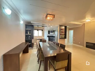 Foto do interior de uma sala de jantar com mesa de madeira escura e armários escuros.