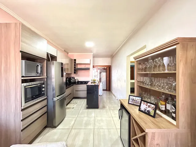 Vista interna de uma cozinha com armários de madeira e piso de cerâmica.