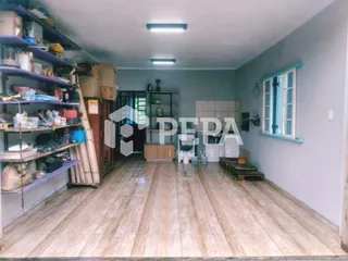 Interior de uma sala com piso de madeira e estantes na parede.