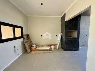 Interior de uma sala em construção com paredes brancas e piso de cerâmica clara.