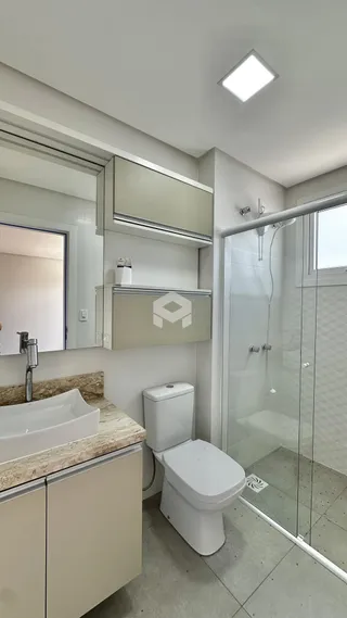 Banheiro com box de vidro e revestimento de cerâmica.