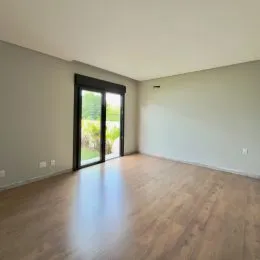Sala de estar com piso de madeira e janela para o exterior.