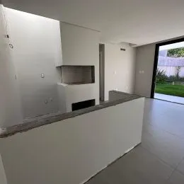 Vista de uma área de cozinha com bancada branca e paredes brancas.
