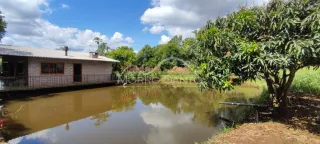 Vista externa de uma propriedade com um corpo d'água e vegetação exuberante.