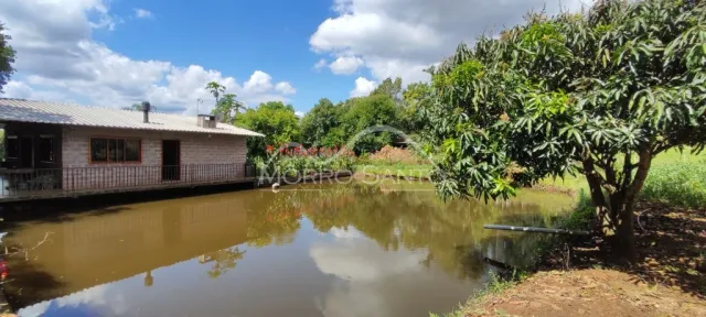 Vista externa de uma propriedade com um corpo d'água e vegetação exuberante.