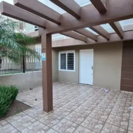 Área externa pavimentada com estrutura de pergolado.