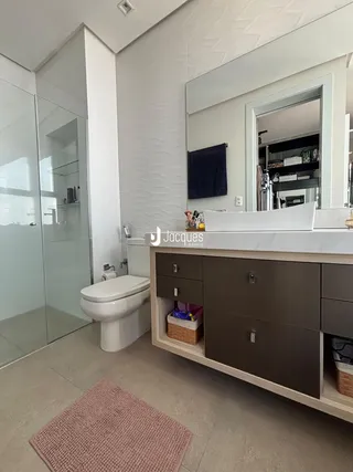 Um banheiro moderno com box de vidro e bancada de madeira.