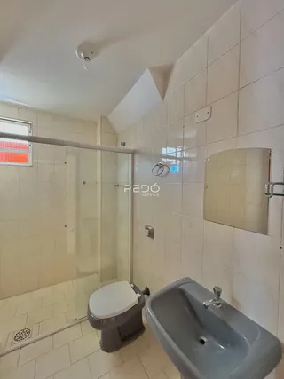 Banheiro com piso de cerâmica e box de vidro.