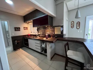 Vista interna de uma cozinha moderna com armários escuros e bancada de madeira.