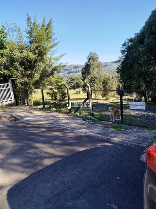 A entrada da propriedade em Lajeado, Brasil, é cercada por uma cerca de madeira e vegetação.