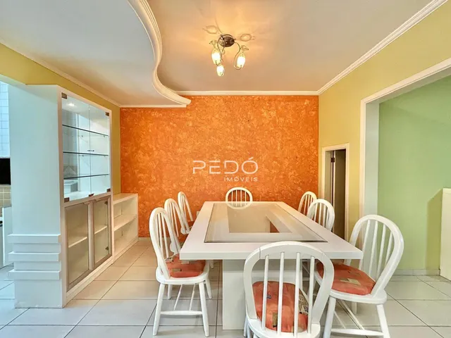 Uma sala de jantar com mesa e cadeiras brancas em um imóvel.