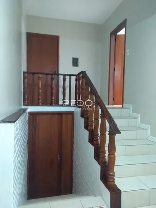 Hall de entrada com escadaria de madeira e portas de madeira.
