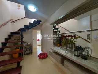 Hall de entrada com escadaria e piso de madeira.