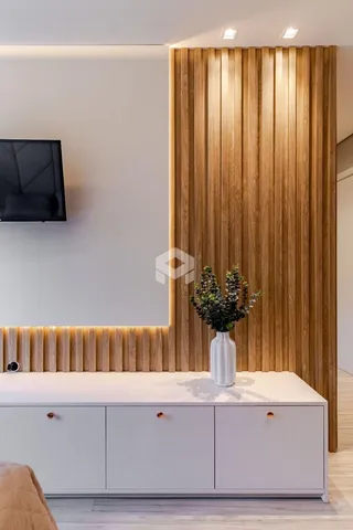 Sala de estar com parede de madeira ripada e móveis brancos.
