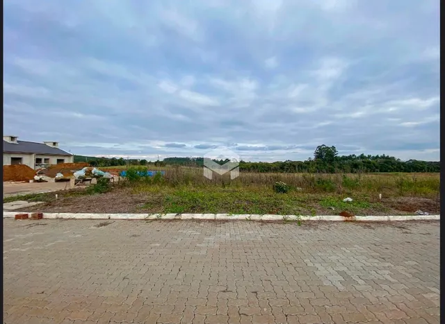 Vista externa de uma propriedade com área pavimentada e vegetação ao fundo.