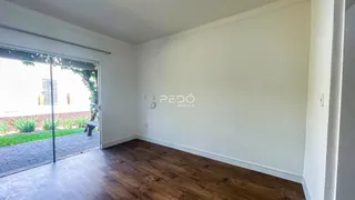 Interior de uma sala com piso de madeira e porta de vidro abrindo para o exterior.