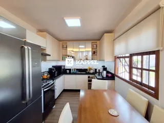 Cozinha moderna com armários brancos e eletrodomésticos em aço inoxidável.