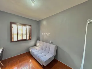 Sala de estar com sofá branco e piso de cerâmica na residência.