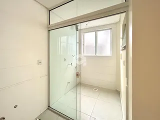 Foto de um banheiro com piso de cerâmica e vidro divisória.