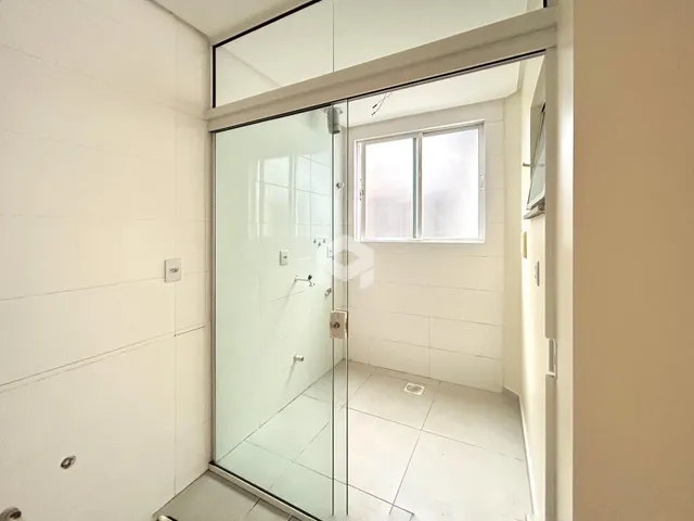 Foto de um banheiro com piso de cerâmica e vidro divisória.
