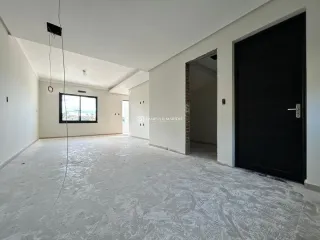 Ambiente interno amplo e vazio com paredes brancas e piso claro.
