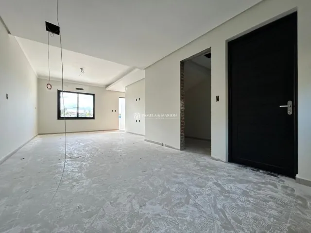 Ambiente interno amplo e vazio com paredes brancas e piso claro.