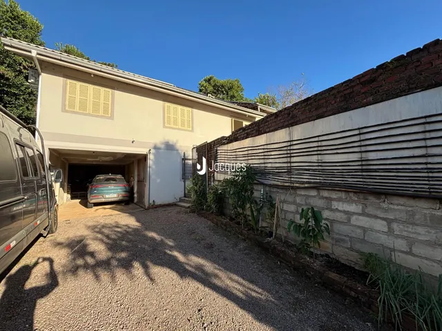 Fachada de uma casa em Lajeado, Brasil, com garagem e muro de tijolos.