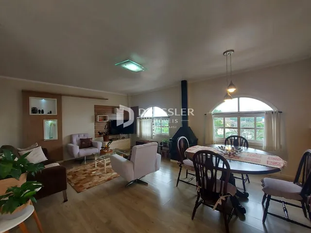 Sala de estar e jantar com piso de madeira e janela arqueada.