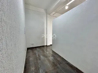 Corredor interno com piso escuro e paredes brancas em uma propriedade.