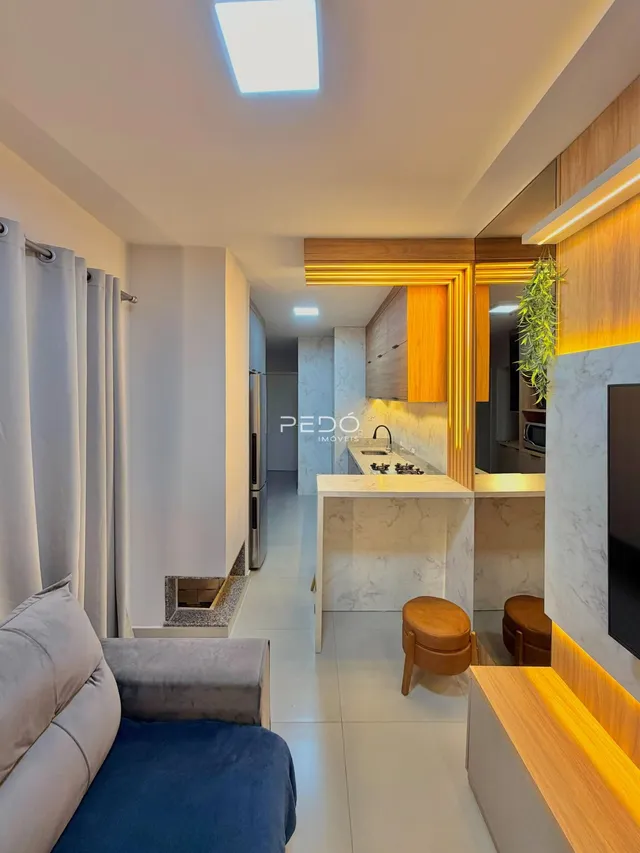 Sala de estar moderna com cozinha integrada em um apartamento em Lajeado.