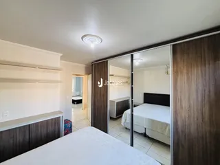 Quarto com cabeceira e painéis de madeira em um imóvel no Brasil.