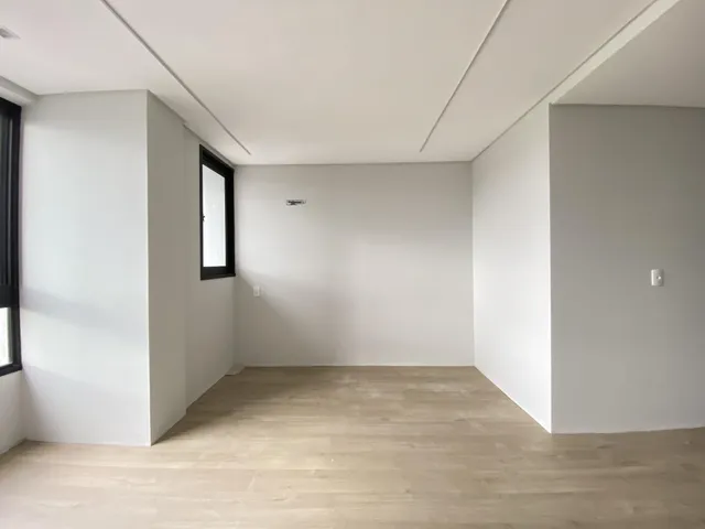 Esta é uma sala de estar ampla com piso de madeira clara e paredes brancas.