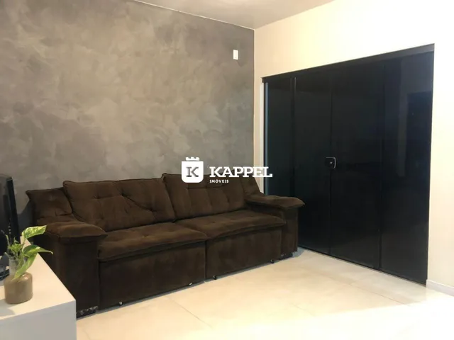 Sala de estar com sofá marrom e armário escuro.